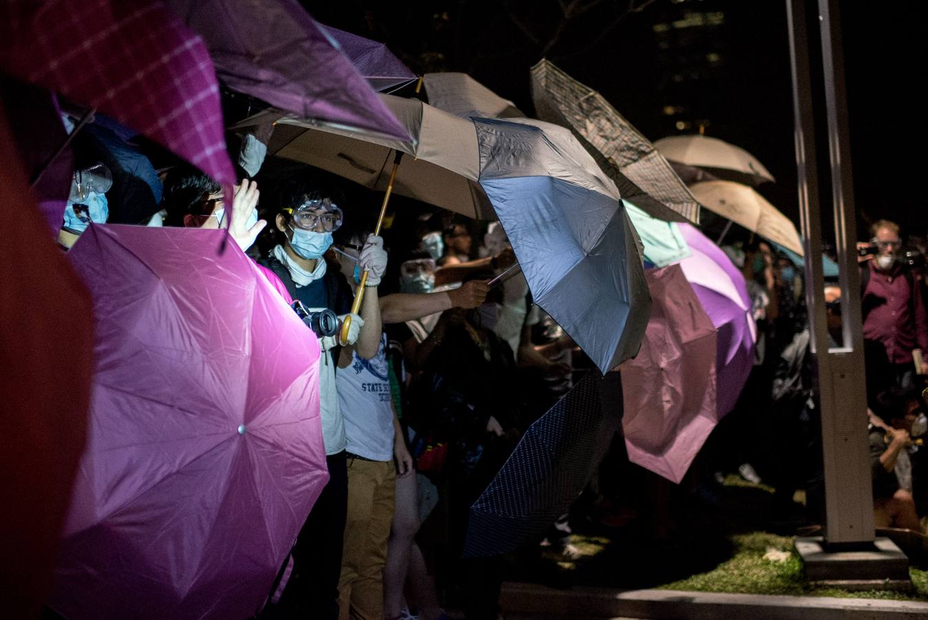 Manifestantes pro-democracia están detrás de los paraguas como anticipo de la policía en sus posiciones cerca de las oficinas del gobierno central en Hong Kong.