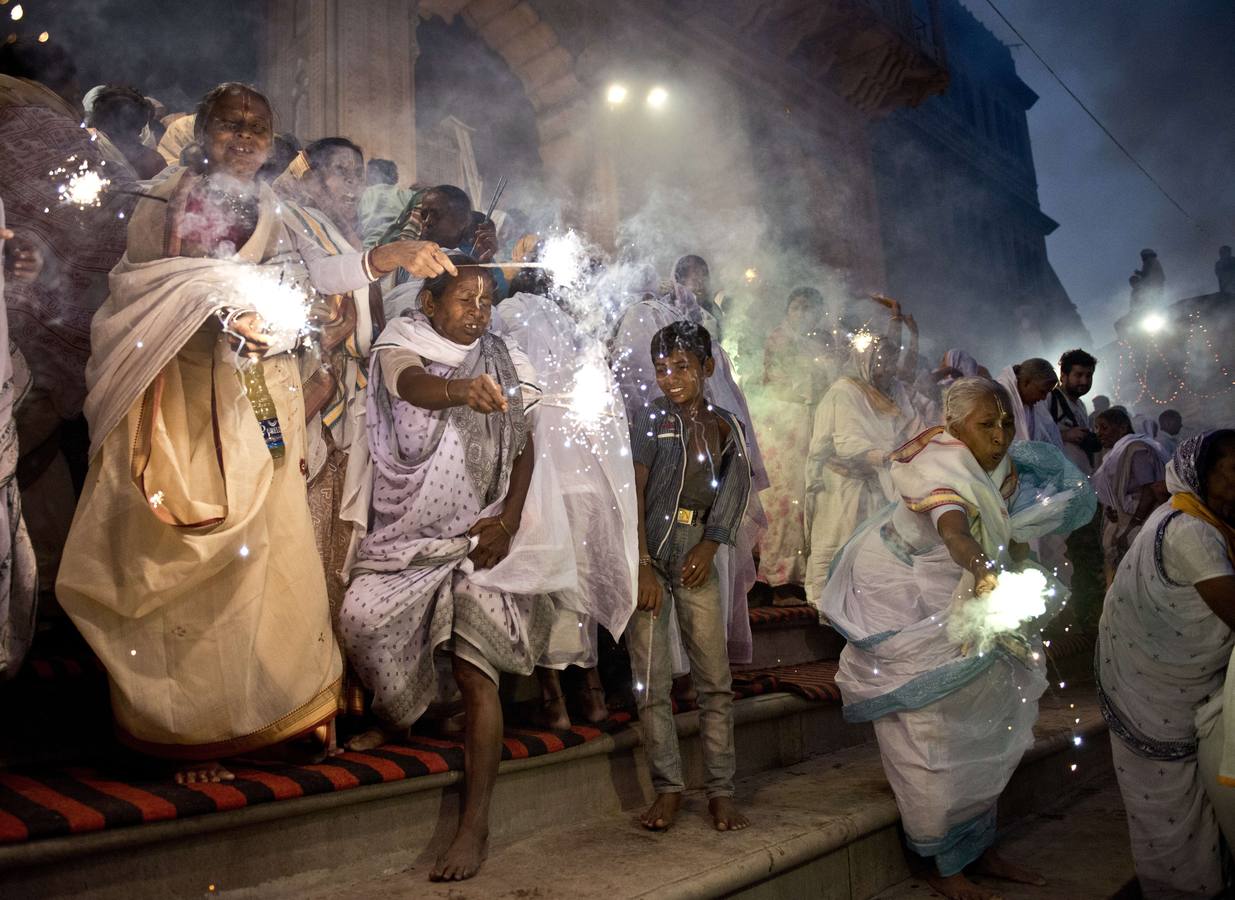 Viudas indias con bengalas mientras participan en una celebración para el festival hindú de Diwali, a orillas del río Yamuna.