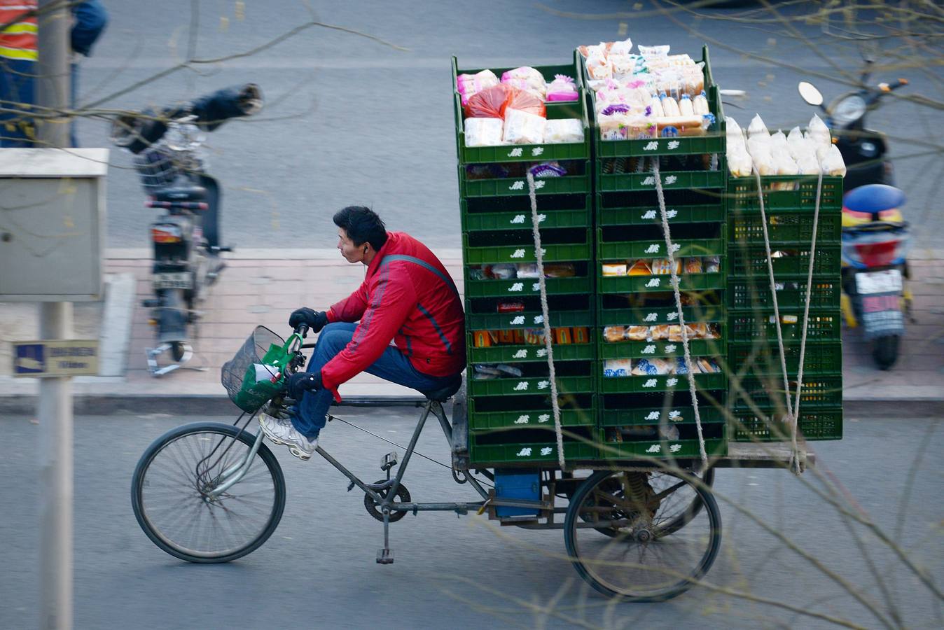 Un vendedor monta un triciclo cargado por una calle de Beijing.