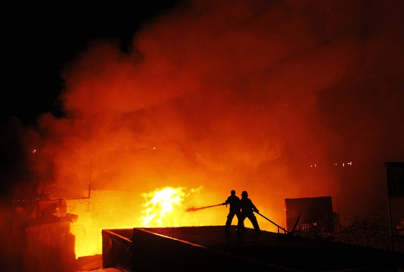 Bomberos filipinos trabajan para extinguir un incendio en una zona residencial de Manila, Filipinas.