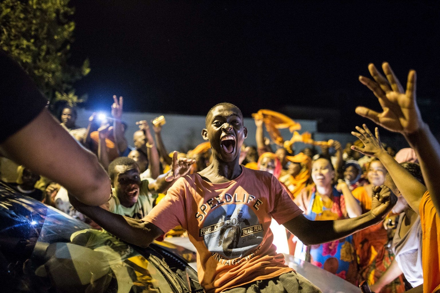 Los partidarios del partido político Orange bailan junto a un centro de votación en Moroni .