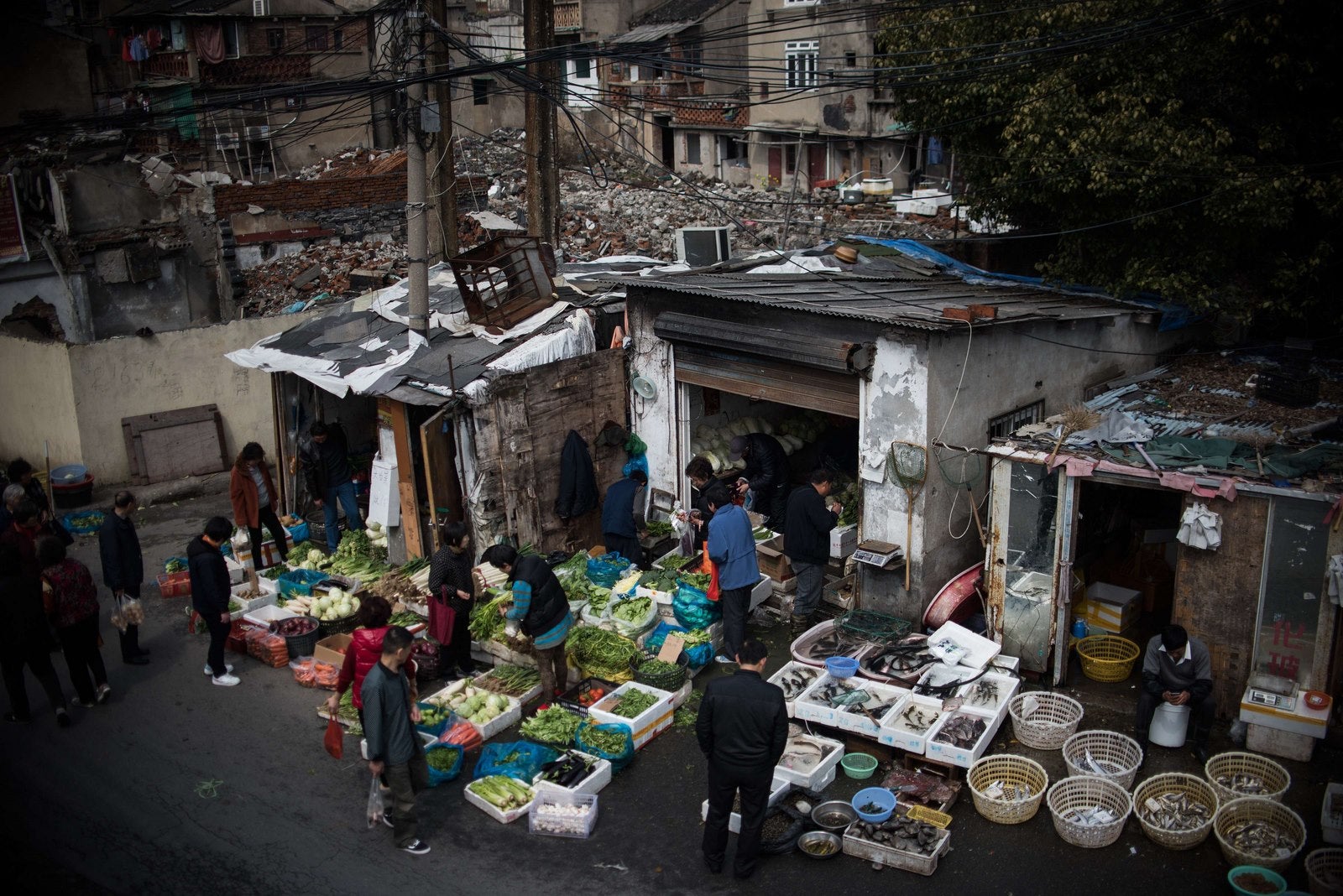 Vendedores venden mercancías en una calle próxima a los edificios demolidos en un barrio residencial de Shanghai.