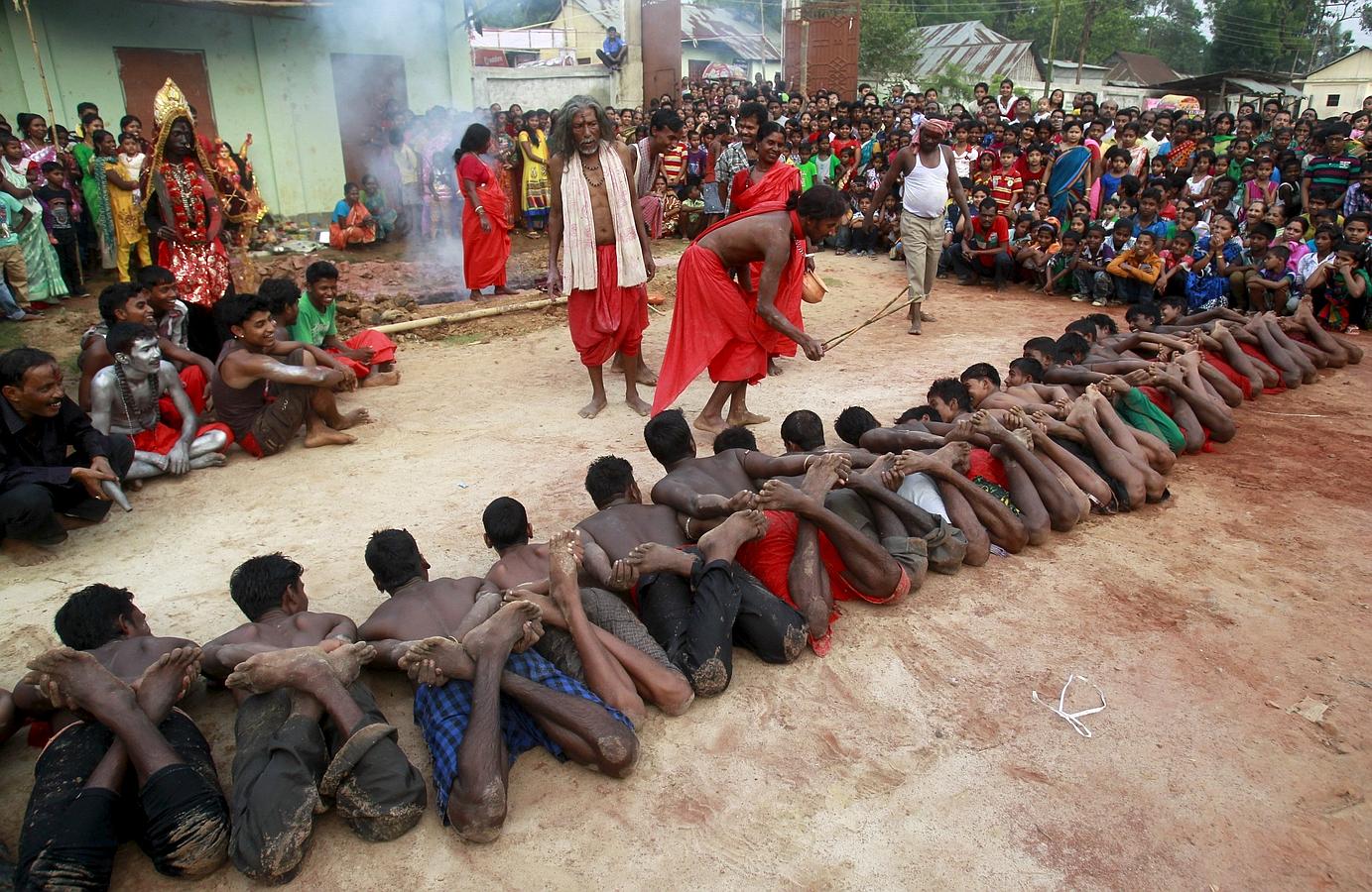 Un sacerdote hindú bendice el ritual con devotos tendidos en el suelo como parte de la fiesta religiosa anual Shiva Gajan en Pratapgarh, en las afueras de la ciudad nororiental india de Agartala.