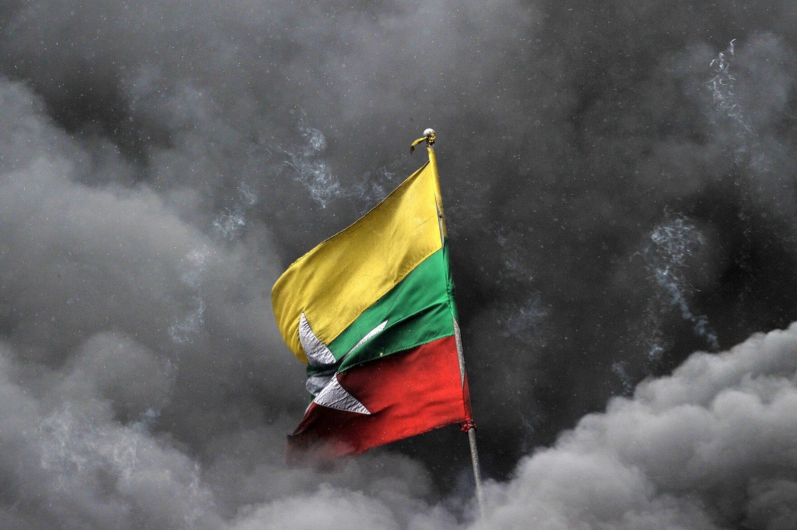 Bandera nacional de Myanmar está rodeada de humo después de quemar montones de drogas incautadas.