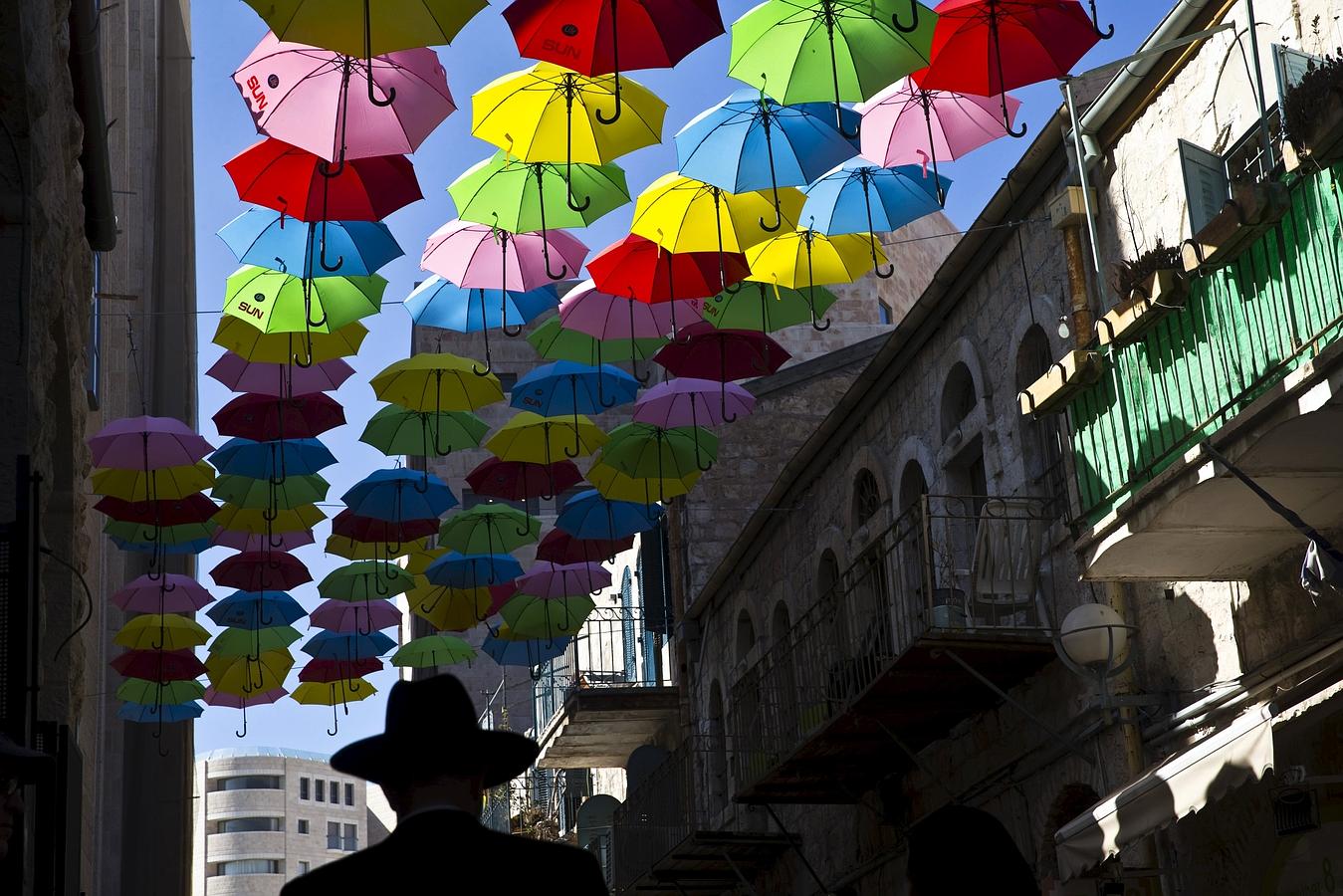 Un hombre camina bajo los paraguas de colores que decoran un paseo peatonal en el centro de Jerusalén.