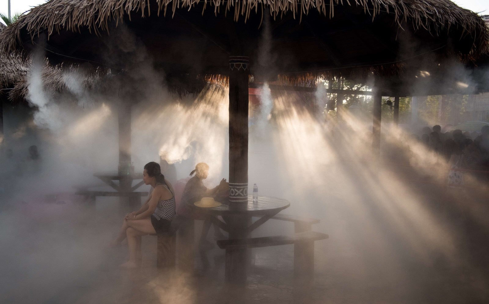 Personas se refrescan debajo de un aspersor en un parque acuático en Shanghai.