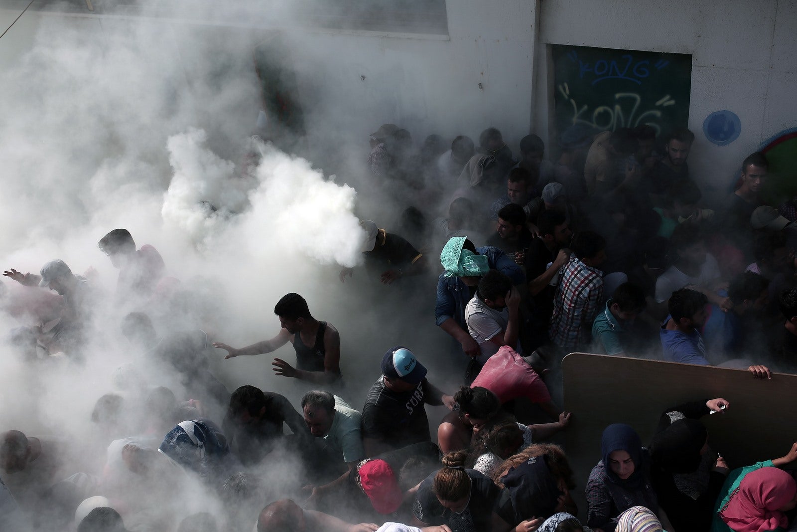 Policías tratan de dispersar a cientos de migrantes rociándolos con extintores durante una reunión para un procedimiento de registro en el estadio, en la isla griega de Kos.