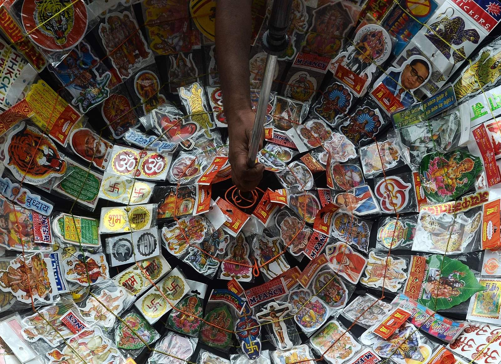 Un vendedor indio vende pegatinas que representan diversas religiones, dioses y diosas espera a los clientes en la esquina de un cruce de caminos en Mumbai.