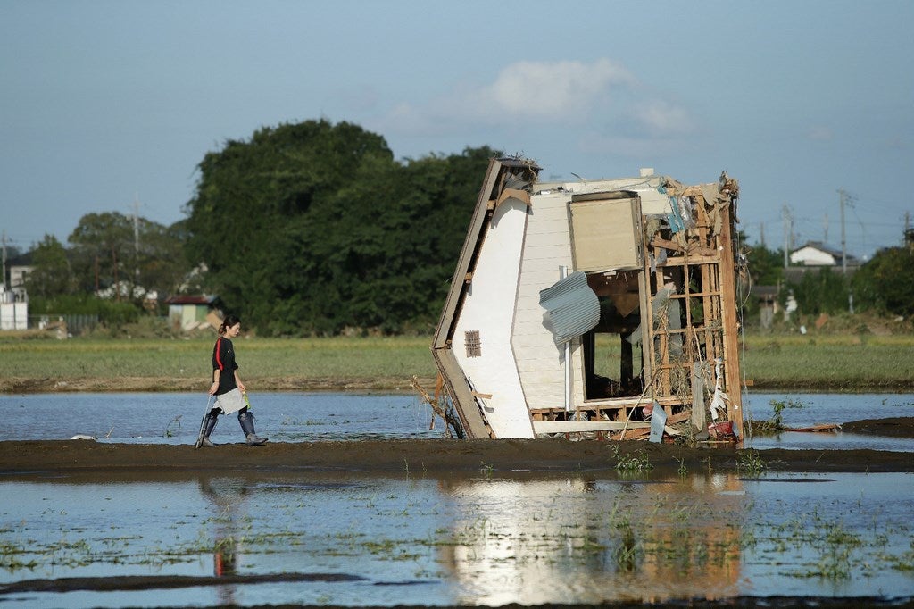 Una mujer camina hacia una casa derrumbada en un campo inundado por las aguas en Joso en la prefectura de Ibaraki, al norte de Tokio.