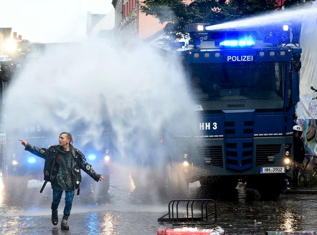 Un manifestante camina delante de los cañones de agua de la policía durante una manifestación contra una manifestación nazi, que fue prohibido por las autoridades, en la calle de Hamburgo Schulterblatt en el barrio de Schanzenviertel.