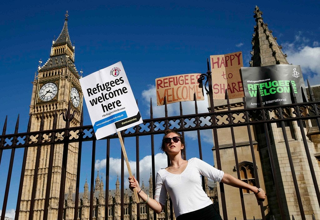 Un manifestante se aferra a la verja exterior de las Casas del Parlamento durante una manifestación para expresar su solidaridad con los inmigrantes, en Londres,