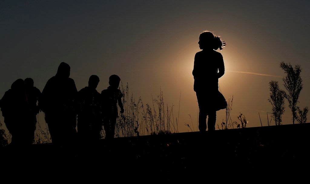 Inmigrantes caminan por las vías de ferrocarril a la puesta del sol cerca de un punto de recogida en Röszke, Hungría.