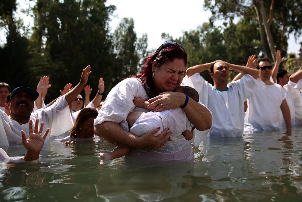 Peregrinos cristianos evangélicos de Brasil levantan sus manos en el aire mientras rezan durante una ceremonia de bautismo en masa, en las aguas del río Jordán en Yardenit en el norte de Israel.
