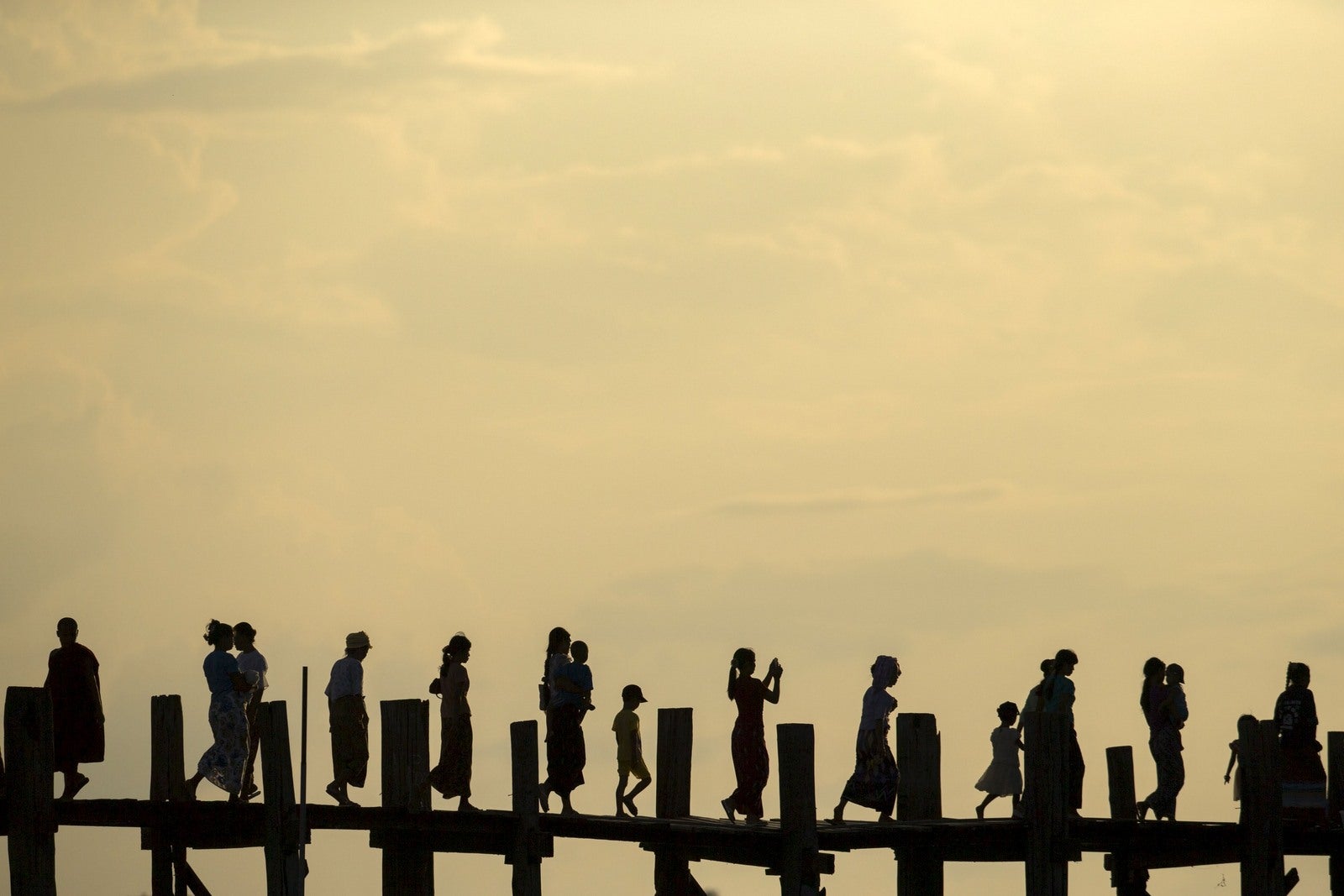 La gente cruza el puente U Bein sobre Tuangthaman Lago en Mandalay, Myanmar.