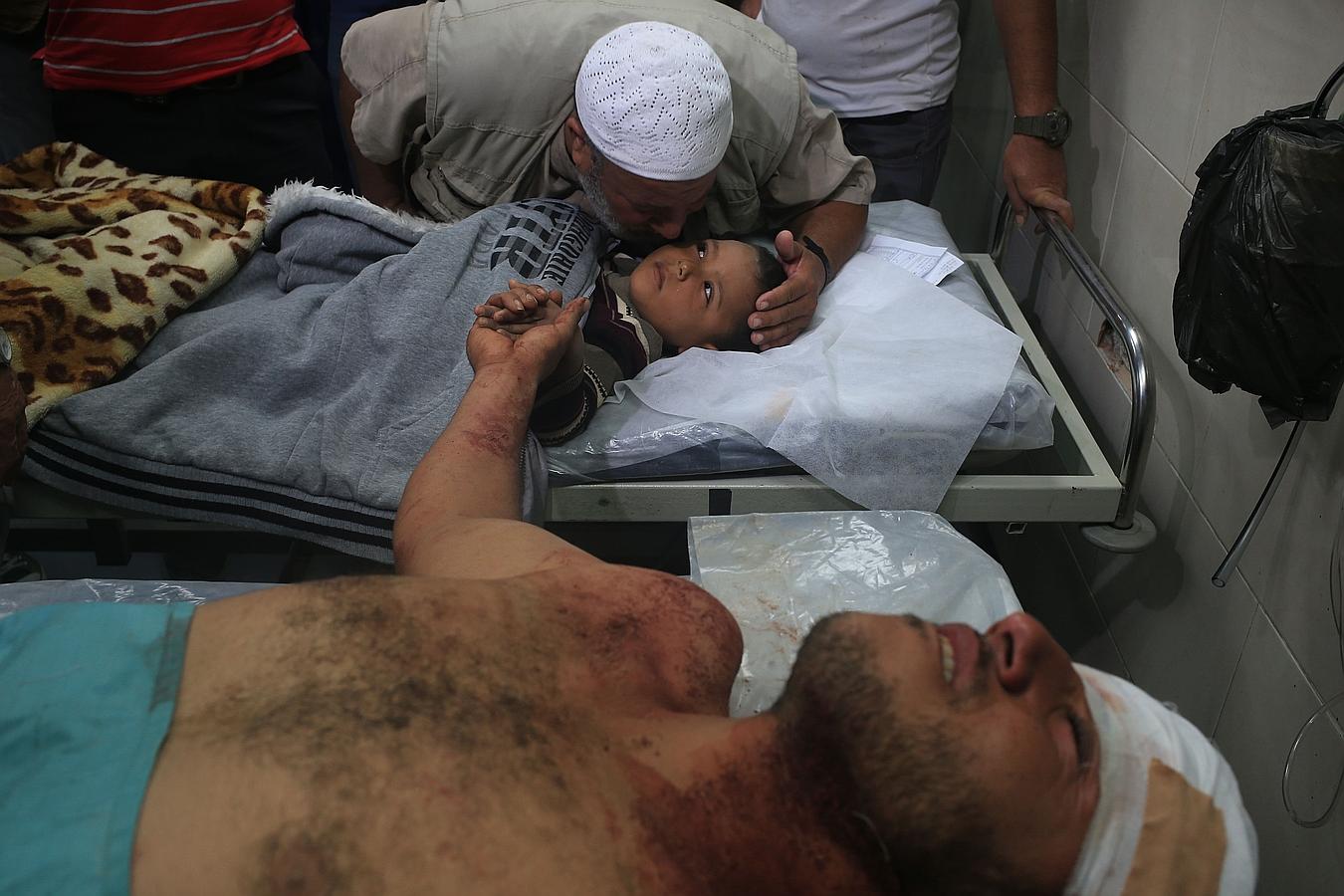 Un niño palestino recibe un beso cogido a la mano de su padre después de que fueron heridos en un ataque aéreo de represalia israelí, en un hospital al-Shifa en la ciudad de Gaza.