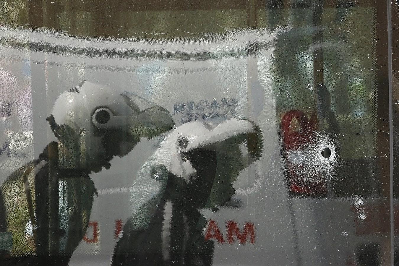 La policía israelí se reflejan en una ventana acribillada a balazos de un autobús después de un ataque en Jerusalén.