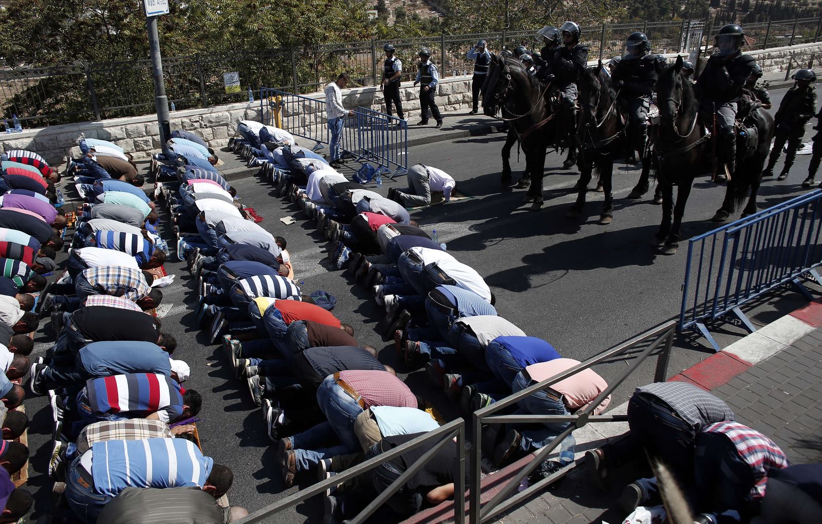 Policía israelí montan guardia mientras musulmanes palestinos rezan en las calles del barrio de Wadi al-Joz en el este de Jerusalén durante la oración del viernes.