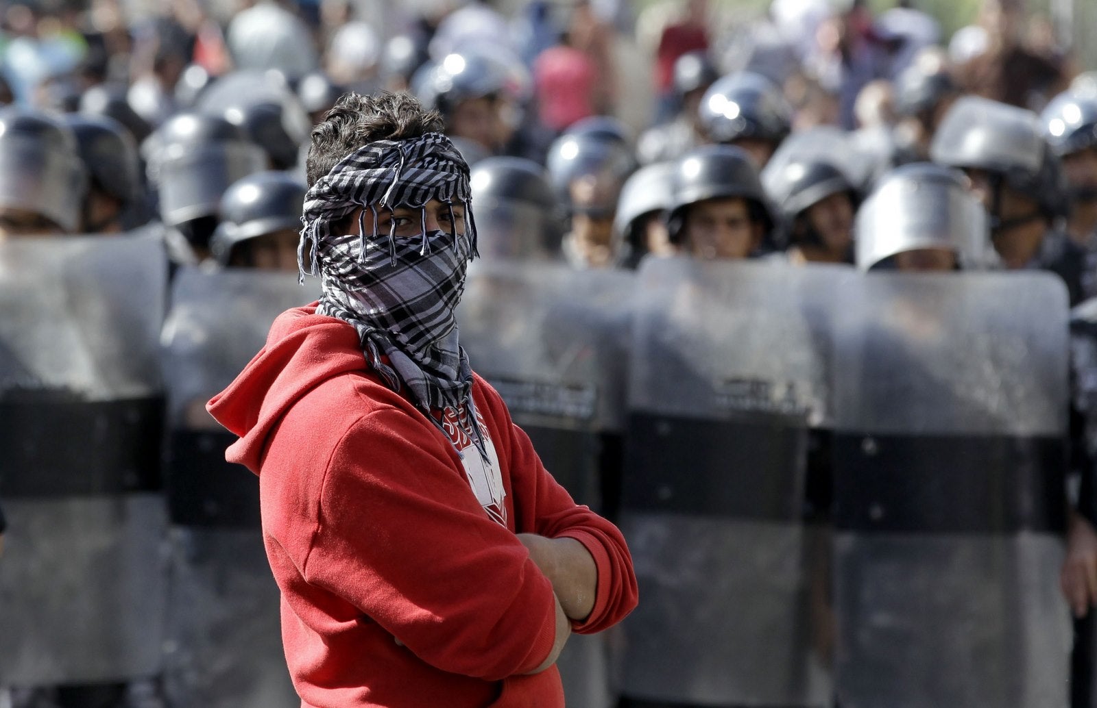 Un manifestante observa mientras la policía antidisturbios jordanos hacen guardia durante una manifestación cerca de la embajada israelí en la capital Amman.