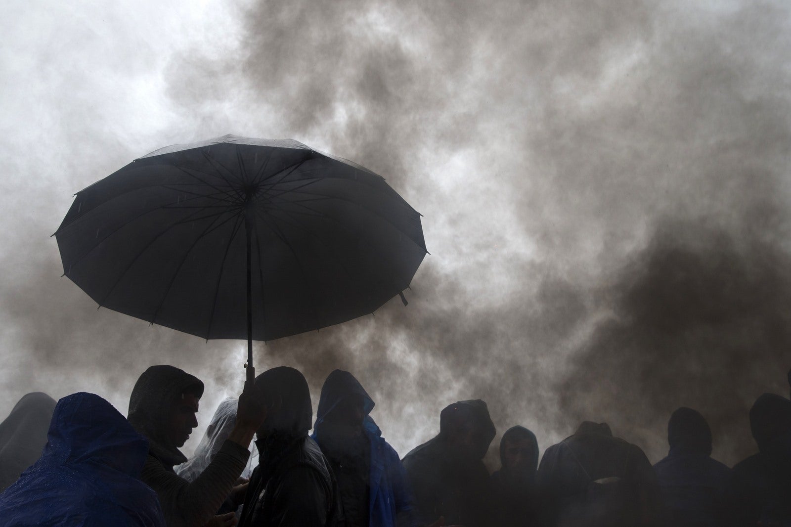 Inmigrantes se protegen de la lluvia, y esperar para cruzar la frontera con Croacia, cerca de la aldea de Berkasovo, Serbia.