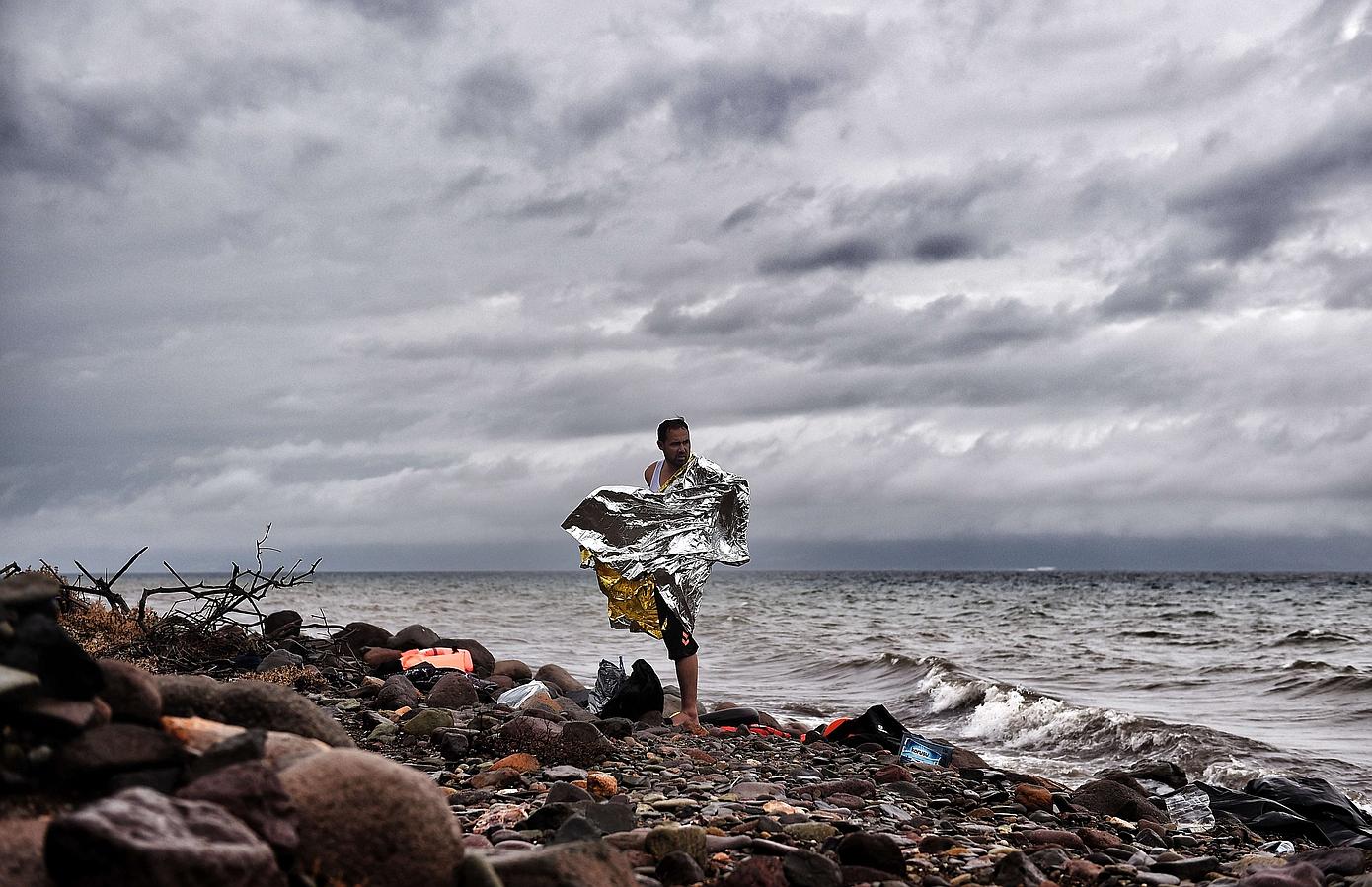 Un hombre se encuentra en la orilla como refugiado. Los inmigrantes llegan a la isla griega de Lesbos después de cruzar el Mar Egeo de Turquía .