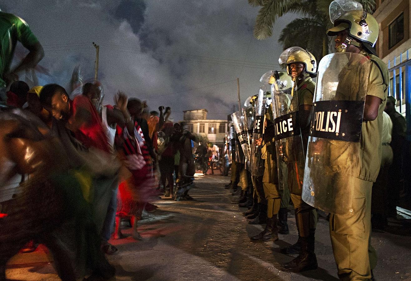 Policía antidisturbios de Tanzania montan guardia mientras que  la gente celebra después de que el candidato de la coalición opositora Maulid Mtulia fue declarado ganador de la circunscripción Kinondoni en Dar es Salaam.