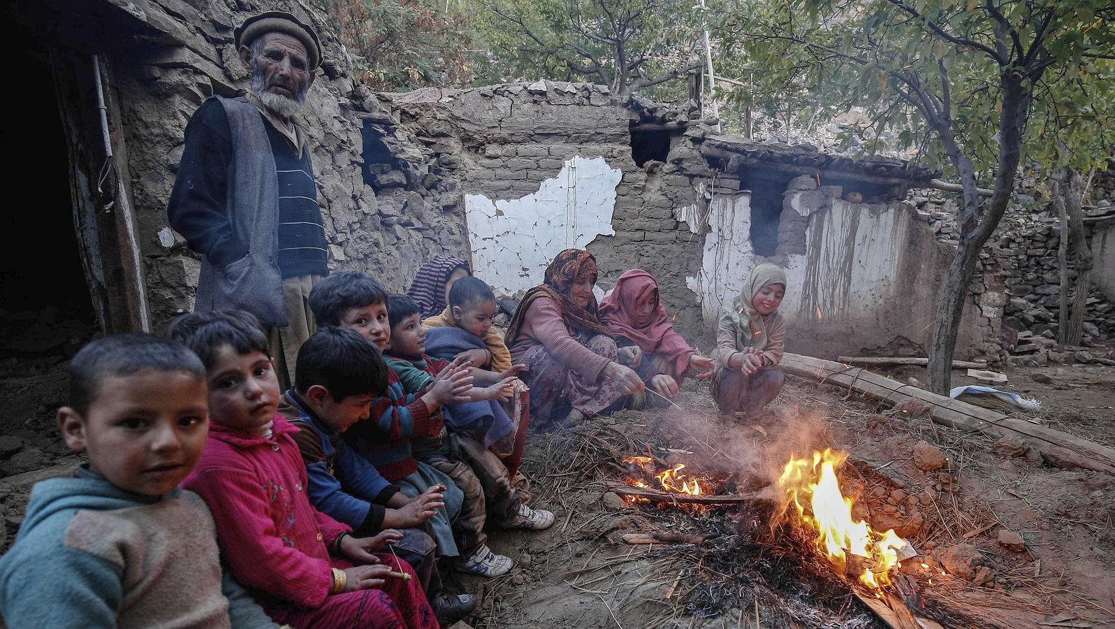 Una familia descansa junto a una hoguera junto a sus casas destruidas en el terremoto de 7,5 grados en Reshun en el valle de Chitral (Pakistán).