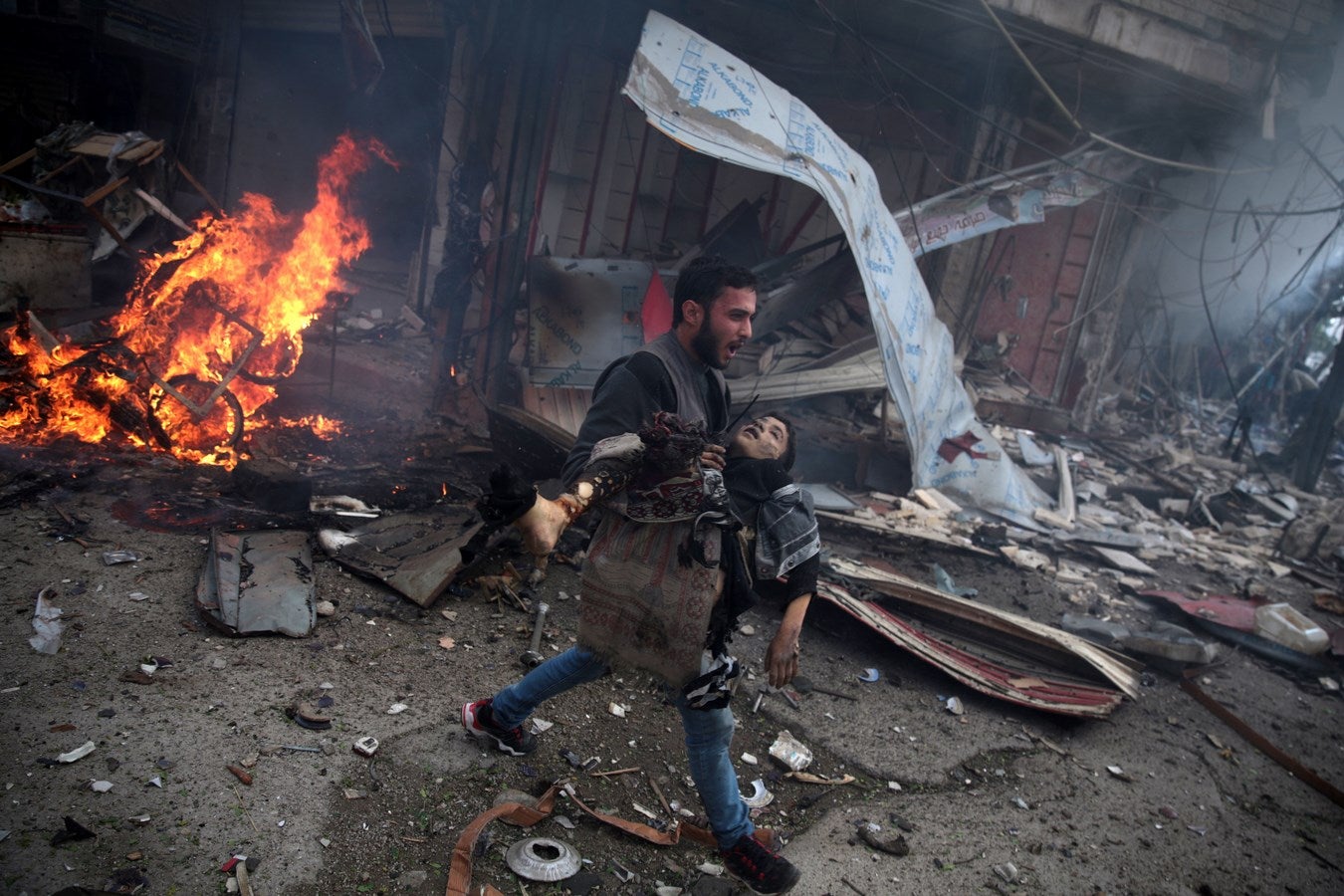 Un hombre sirio lleva el cuerpo de un niño muerto en un ataque aéreo realizado por las fuerzas gubernamentales en la zona controlada por los rebeldes de Douma, al este de la capital Damasco.