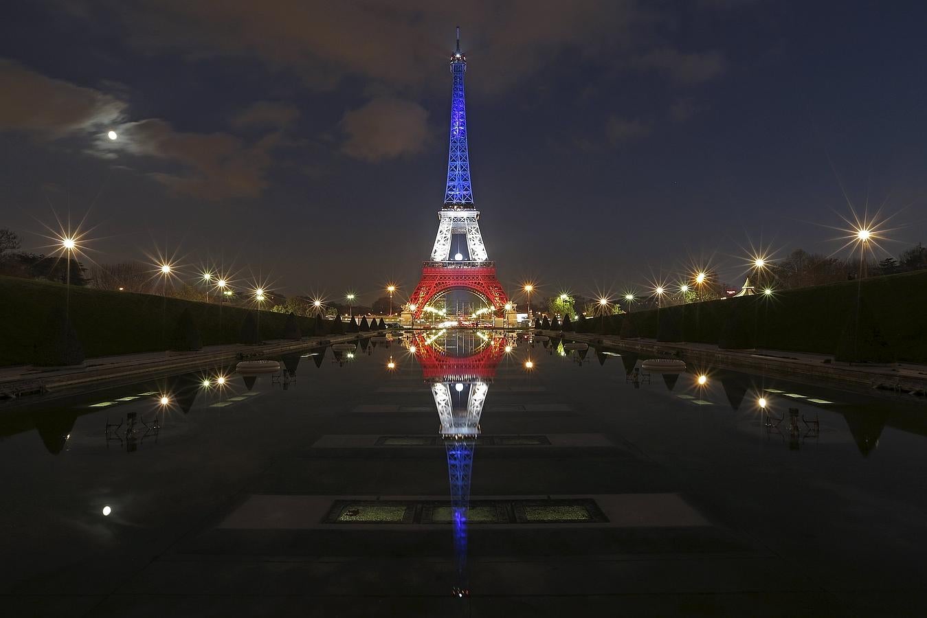 La Torre Eiffel iluminada con los colores azul, blanco y rojo de la bandera francesa se refleja en las fuentes de Trocadero en París, Francia.