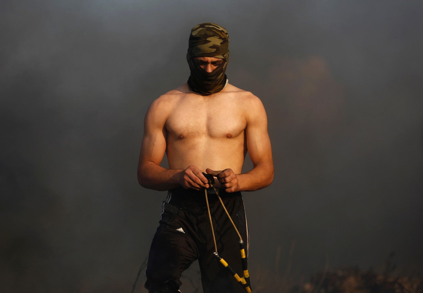 Un manifestante palestino enmascarado prepara una honda durante los enfrentamientos con las fuerzas de seguridad israelíes.