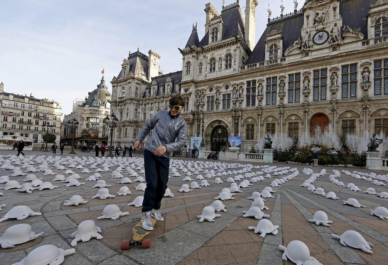 Un hombre monta sobre una patineta a través de la instalación del artista francés Rachid Khimoune que cuenta con un millar de esculturas con forma de tortuga, en frente de la alcaldía de París, Francia.