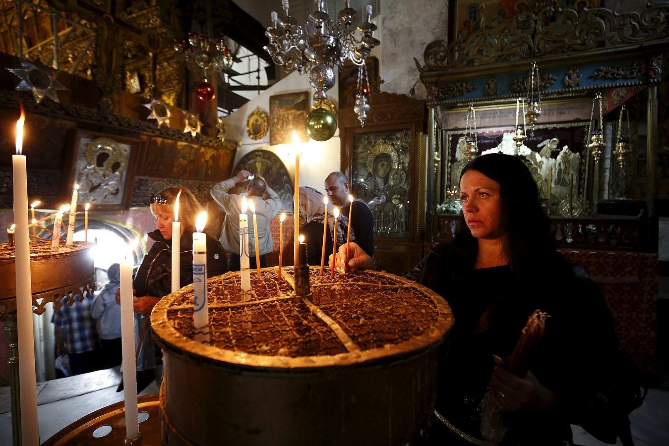 Una devota enciende velas en el interior de la Iglesia de la Natividad, en la ciudad cisjordana de Belén.