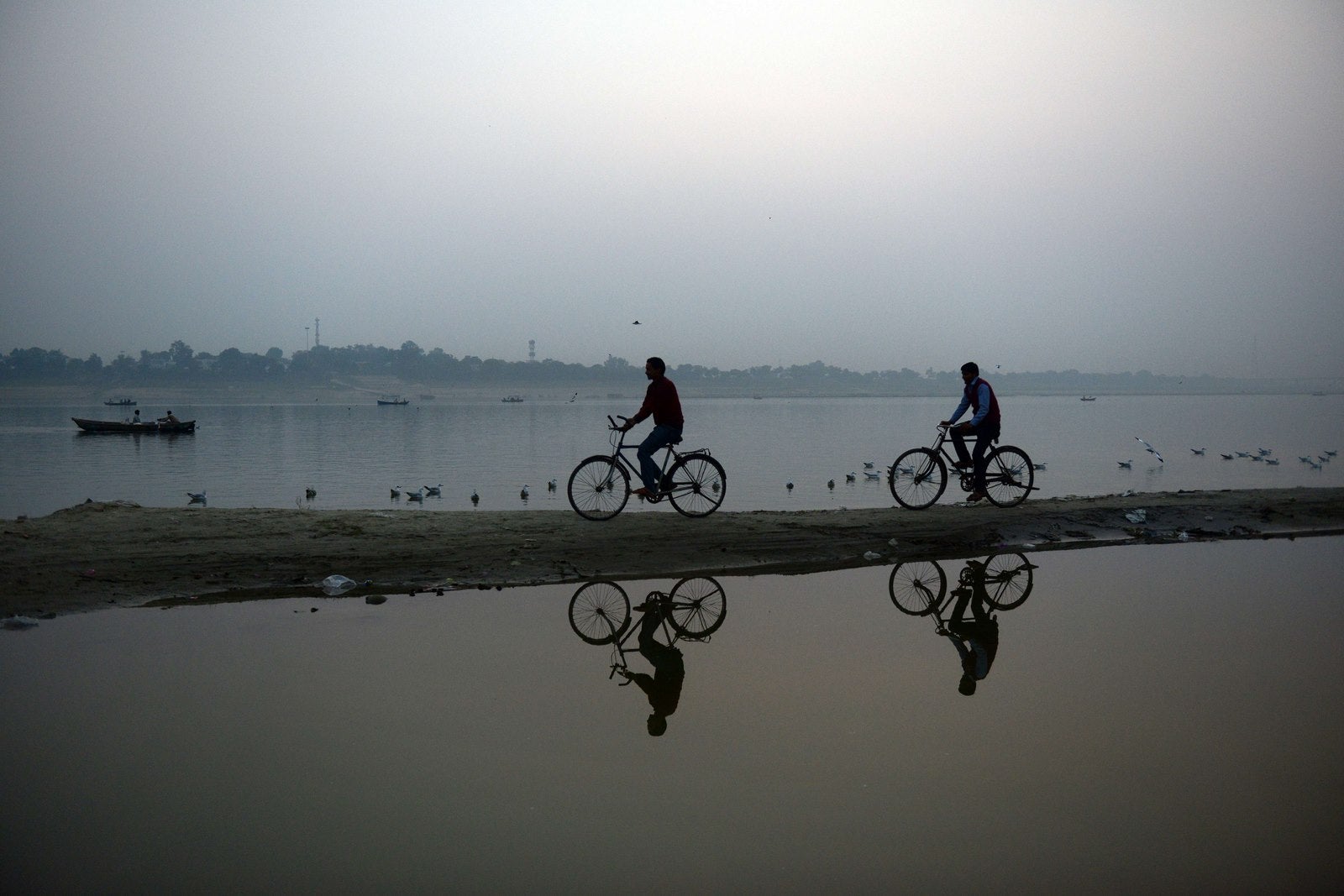 Ciclistas indios pasan a lo largo de los bancos en Sangam, la confluencia de los ríos Ganges, Yamuna y el mítico Saraswathi, en Allahabad.