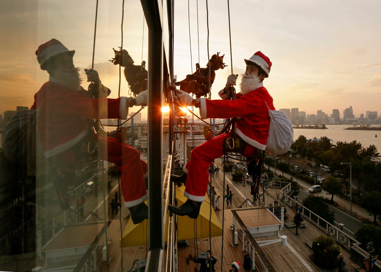 Un trabajador vestido de Papá Noel limpia Los Cristales de un centro comercial en Tokio (Japón).