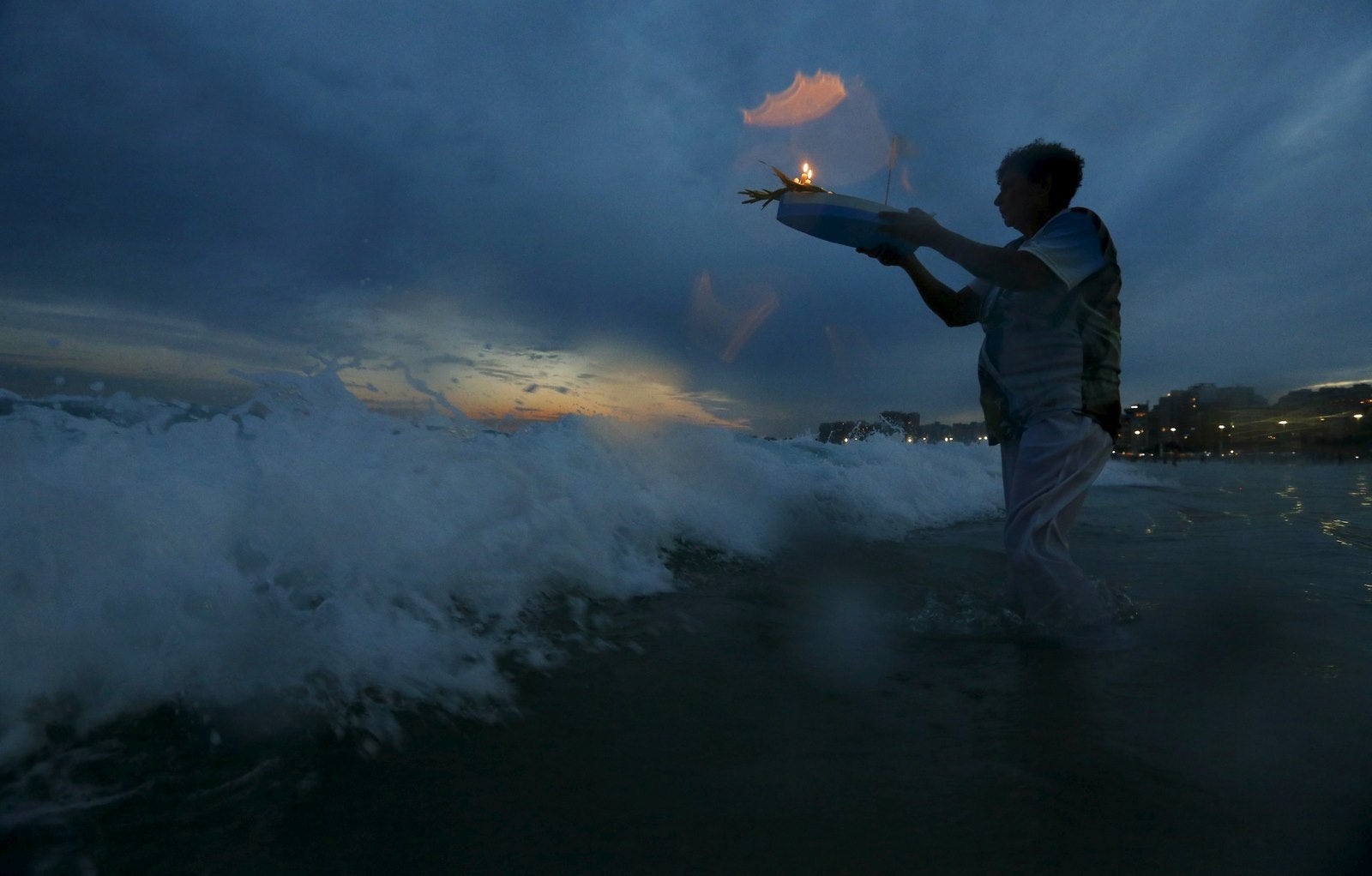 Un seguidor de la religión afrobrasileña Umbanda lleva ofrendas para Iemanjá, la diosa del mar, en la playa de Copacabana en Río de Janeiro.