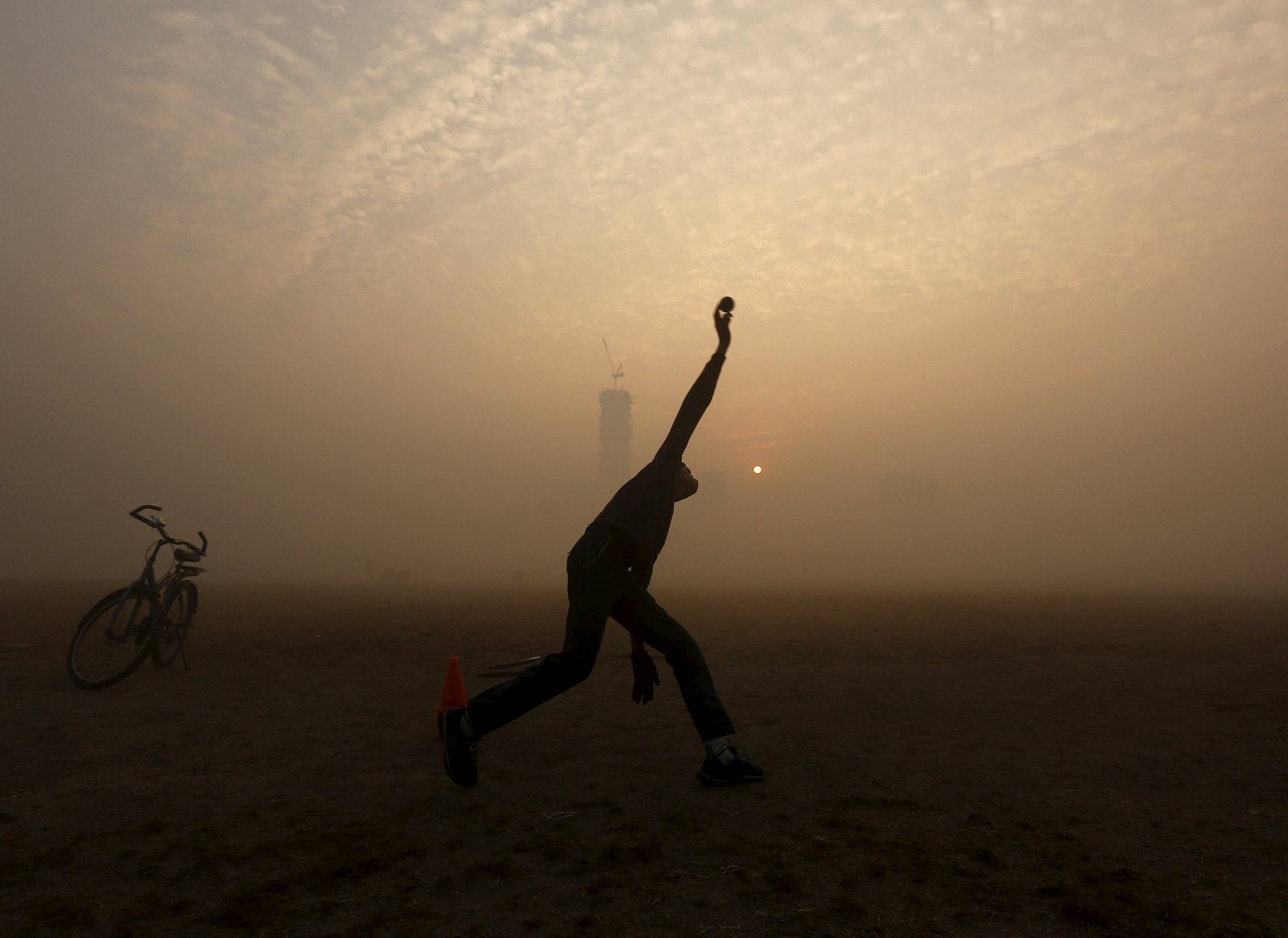Un niño cuencos mientras que jugar al cricket en un parque público en medio de una densa niebla en una fría mañana de invierno en Kolkata, India, 30 de diciembre de 2015.