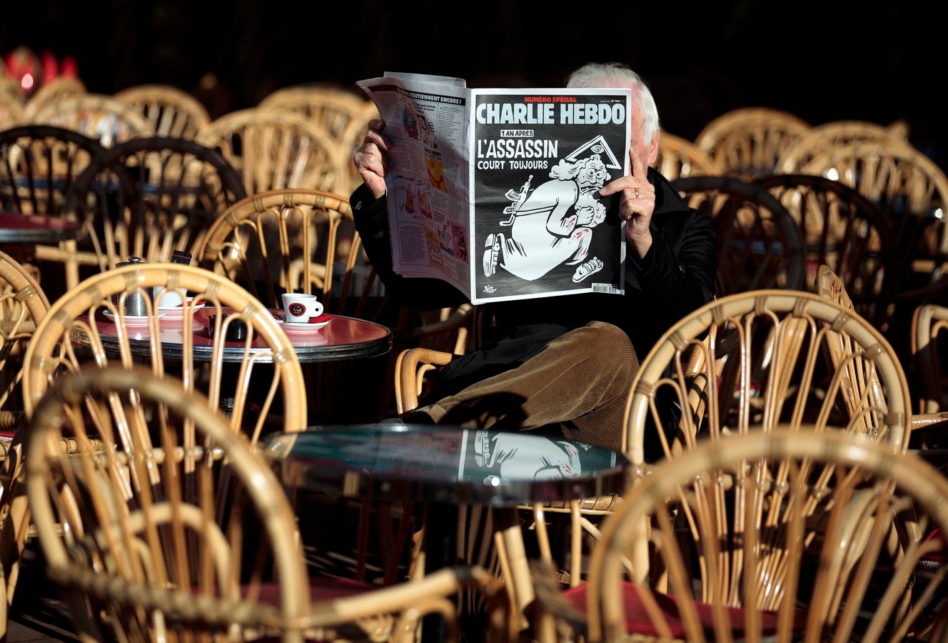 Un hombre lee la última edición del semanario francés Charlie Hebdo con el título "Un año después, el asesino sigue en la carrera" en una terraza del café en Niza, Francia.