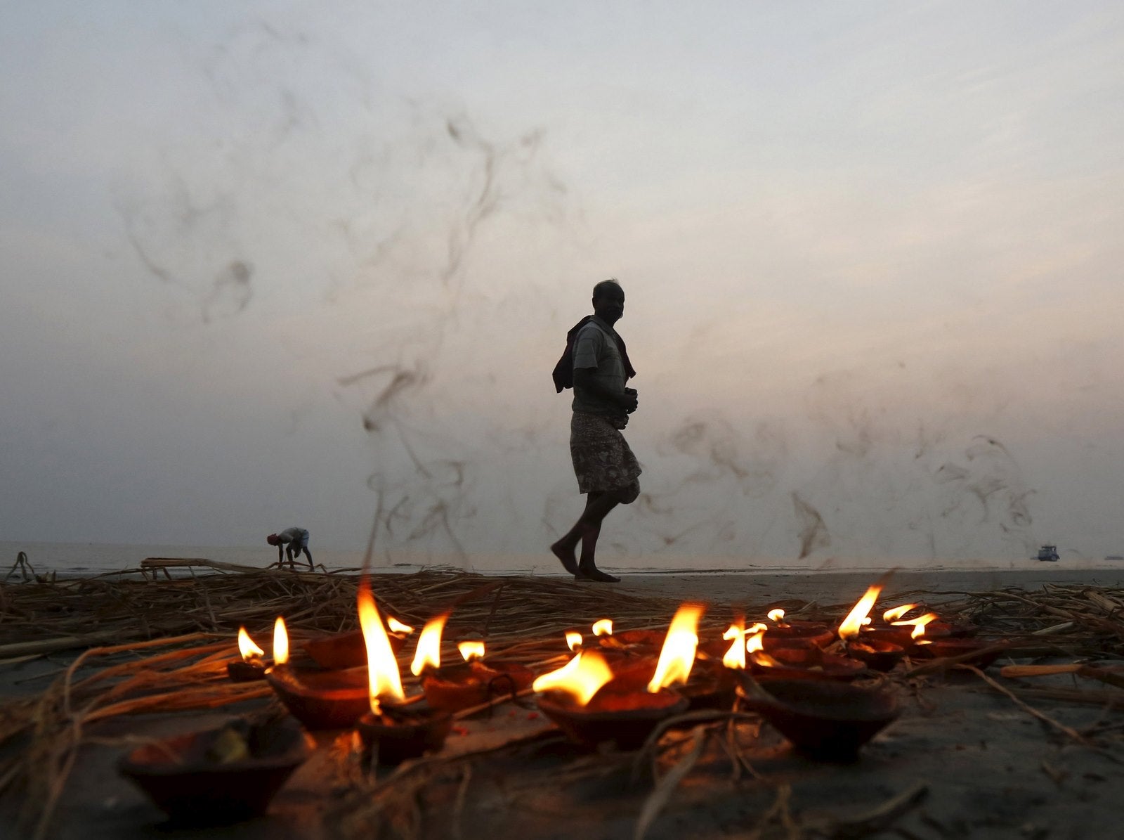 Un peregrino hindú pasa junto a una hilera de lámparas encendidas después de tomar un baño sagrado en la confluencia de los ríos Ganges y la Bahía de Bengala en Sagar Island, al sur de Calcuta, India.
