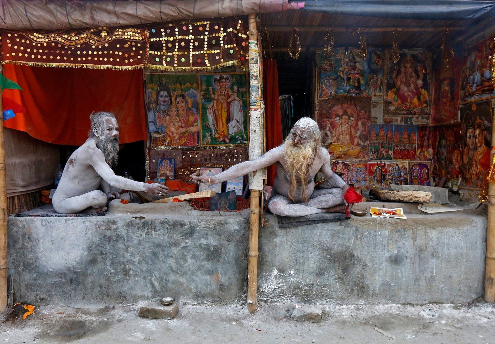 Santones hindúes, manchados de ceniza, fuman dentro de sus campamentos improvisados cerca de la confluencia del río Ganges y la Bahía de Bengala, por delante del festival "Makar Sankranti" en Sagar Island, al sur de Calcuta, India.