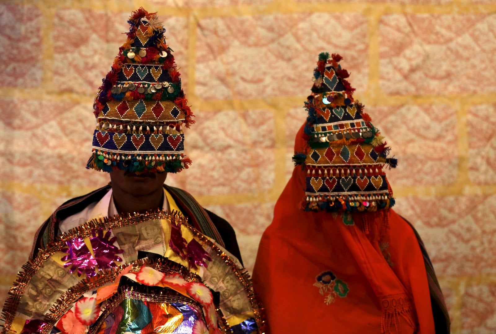Una novia y el novio llevaba guirnaldas hechas a mano tradicionales esperan su boda para comenzar durante una ceremonia de matrimonio en masa en Karachi, Pakistán.