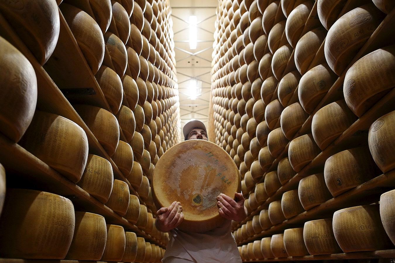 Un trabajador lleva un queso de parmesano fuera de la plataforma del almacén de la cooperativa lechera 4 Madonne Caseificio dell'Emilia en Módena, Italia.