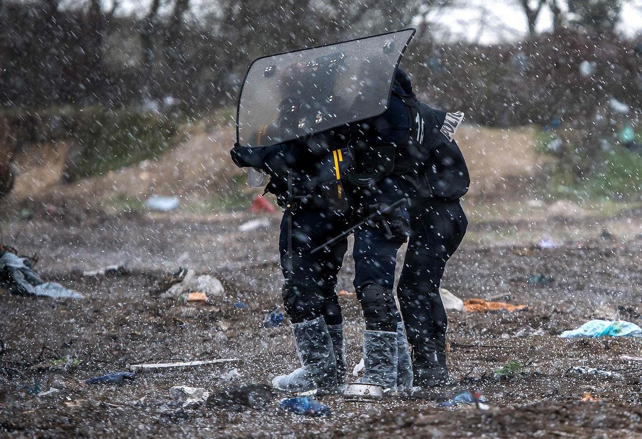 La policía antidisturbios se protege de una tormenta de granizo, durante la demolición de la parte sur del llamado campo de inmigrante "selva",, en Calais.
