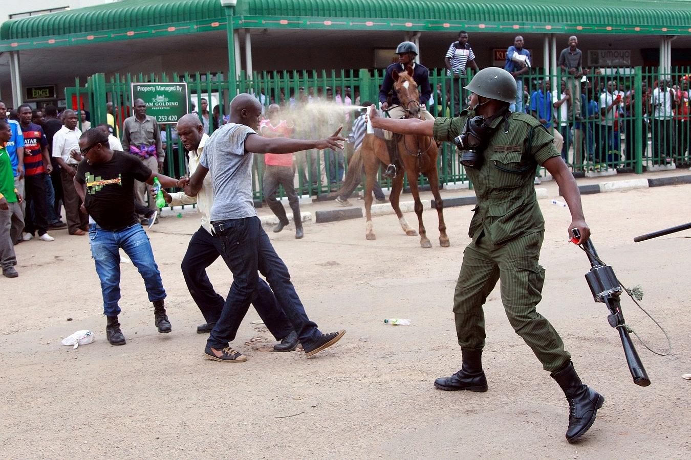 Un oficial de policía usa un spray de pimienta contra los partidarios de la oposición, Partido Unido para el Desarrollo Nacional (UPND) a las afueras de la estación de policía de Woodlands en Lusaka.