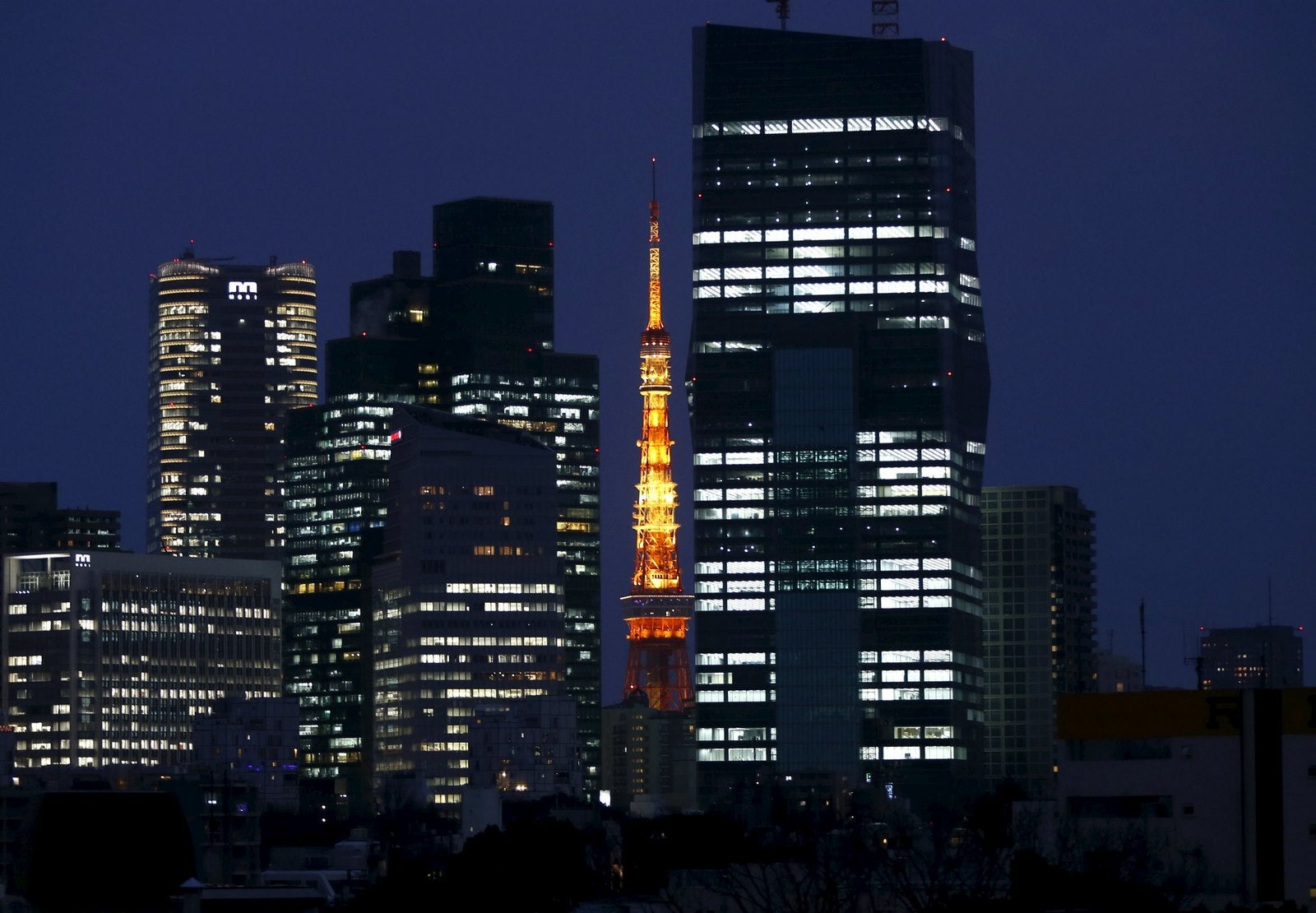 Una Torre de Tokio iluminada se observa entre rascacielos en Tokio, Japón.