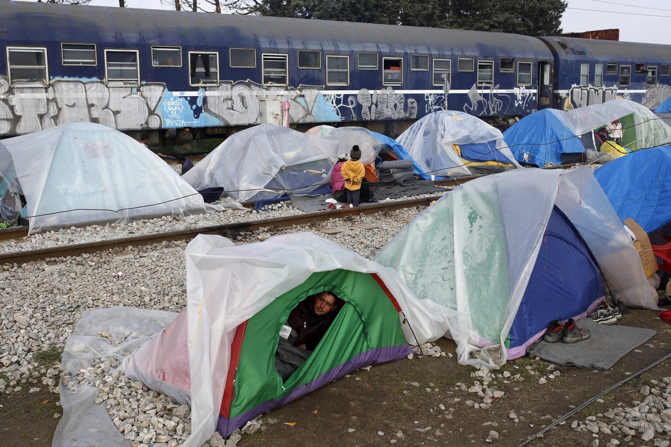 Un migrante mira hacia fuera de su tienda de campaña en un campamento improvisado para los migrantes y refugiados en la frontera entre Grecia y Macedonia, cerca de la localidad de Idomeni, Grecia.