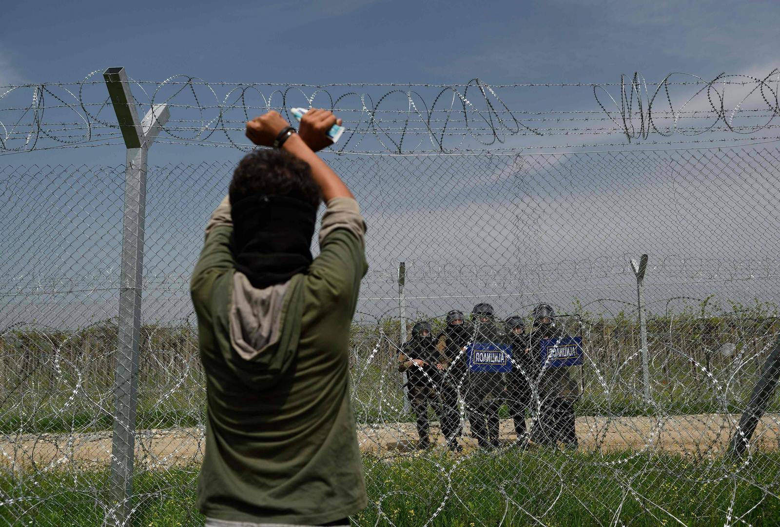 Un hombre mira a la policía Macedonia a través de una cerca como inmigrantes y refugiado realiza una protesta para pedir la reapertura de la frontera cerca de su campamento improvisado en la frontera entre Grecia y Macedonia en Idomeni.