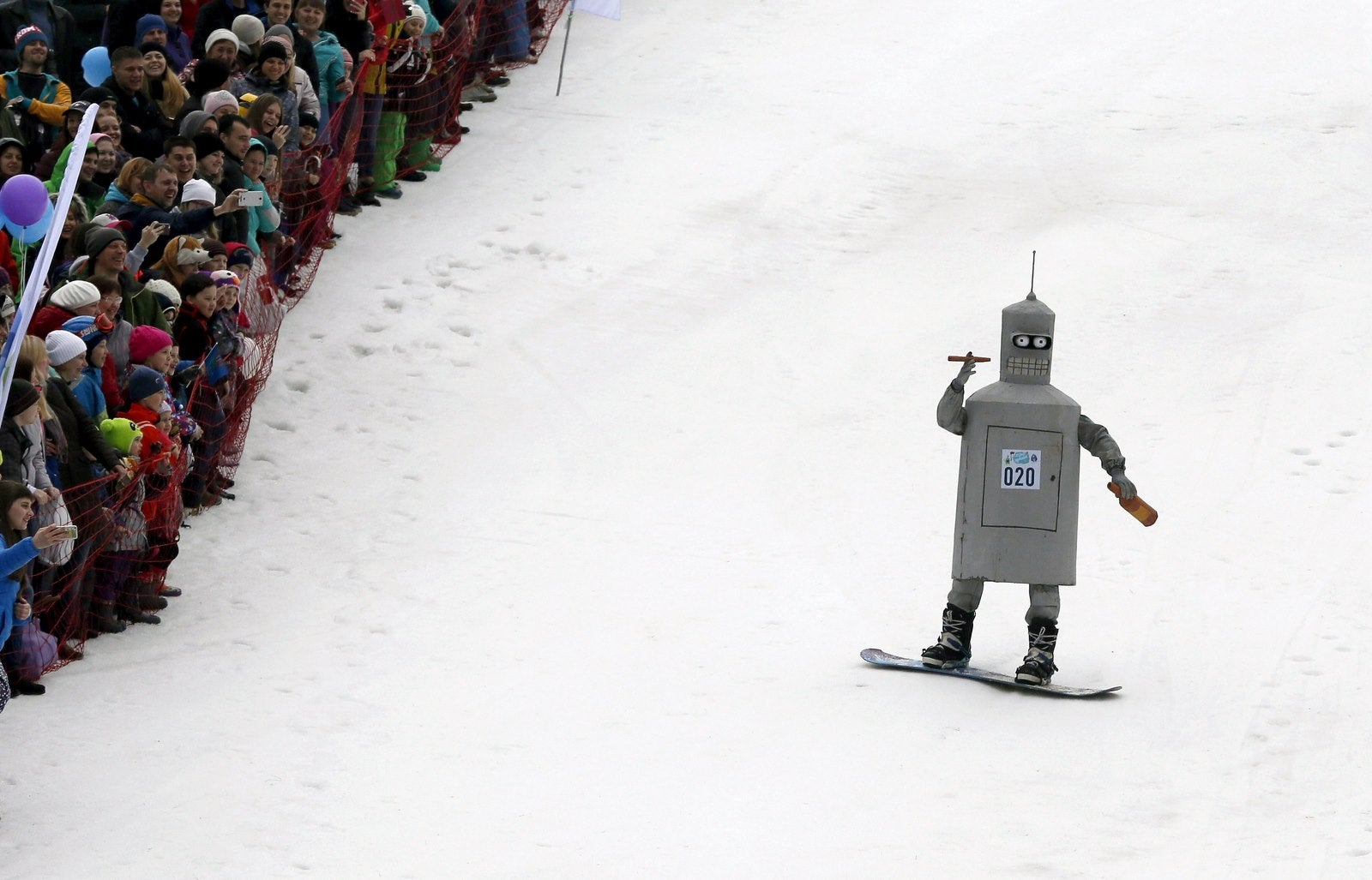 Los espectadores observan un snowboarder en un traje de lujo, se desliza hacia abajo antes de que un intento de cruzar un charco de agua a los pies de una pista de esquí en la estación de esquí Bobrovy sesión en las afueras de la ciudad siberiana de Krasnoyarsk, Rusia