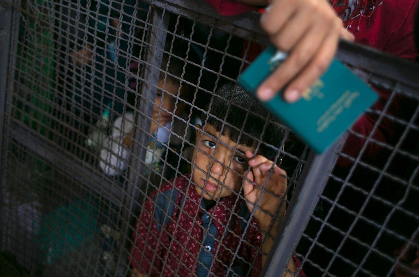 Un niño palestino mira a través de una barrera, mientras espera en la frontera de Rafah con Egipto, en el sur de la Franja de Gaza