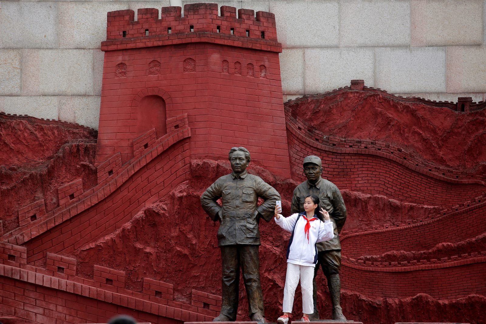 Una niña hace una foto con estatuas que representan al presidente chino Mao Zedong y ex general Zhu De, durante la Guerra de Resistencia contra el Japón, en Jianchuan Museo Cluster en Anren, provincia de Sichuan, China