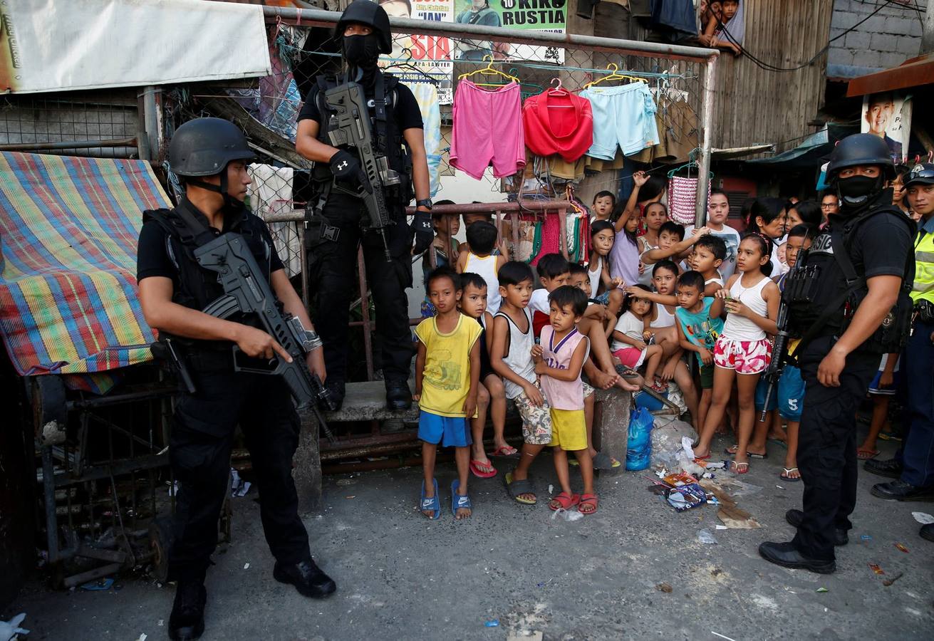 Miembros del equipo SWAT de la Policía Nacional de Filipinas hacen guardia cerca de los residentes durante una operación antidrogas, en Pasig, Metro Manila, Filipinas.