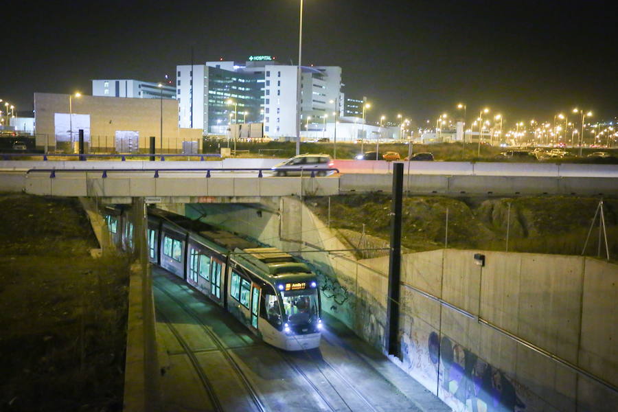 El metro de Granada, durante una prueba nocturna camino de Armilla, con el hospital del PTS al fondo.